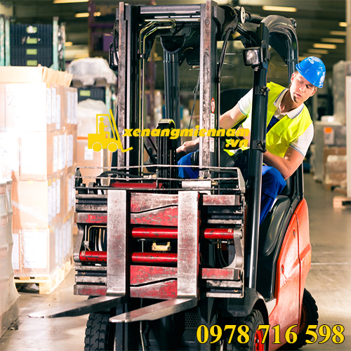 forklift driver in protective vest driving forklift at warehouse of freight forwarding company